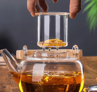 Glass teapot being heated on a gas stove with tea brewing inside