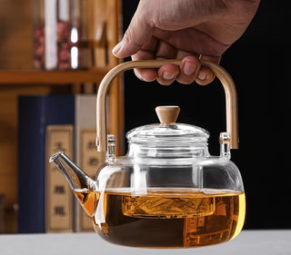 Pouring brewed tea from glass teapot into a glass cup